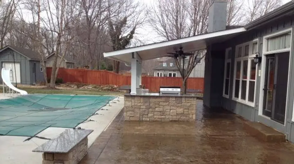 A pool closed under its winter cover beside an empty covered patio, the off-season stretch when the phone stops ringing.