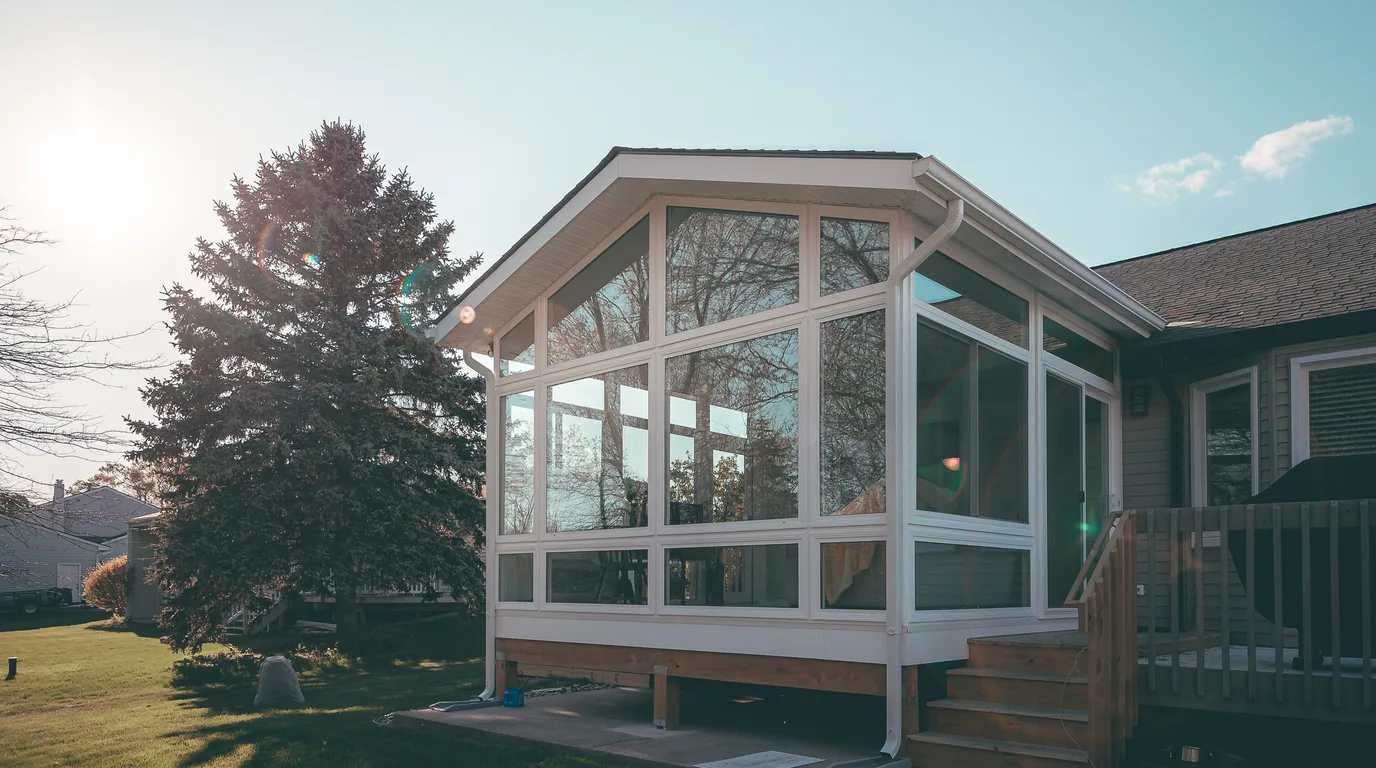 A finished premium sunroom addition on a real home in warm daylight, representing the five-figure job at stake when a lead goes unworked.