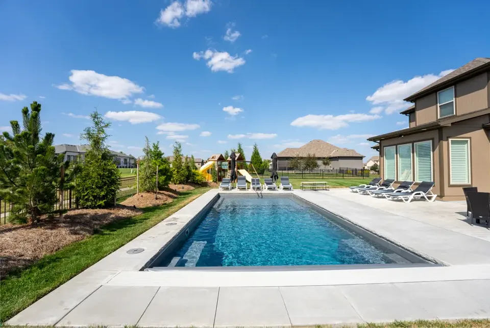 A calm inground pool in a modern backyard in daylight with clear blue water