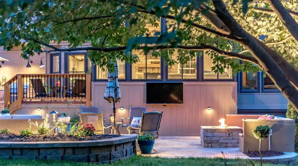 A finished backyard at dusk, patio lit and fire feature burning, the kind of outdoor living work Atlantic Media markets