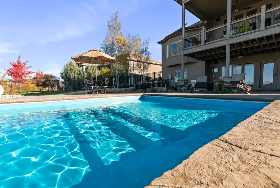 Pool craftsmanship up close: tiled entry steps, clean coping, and a paver deck running to the water.